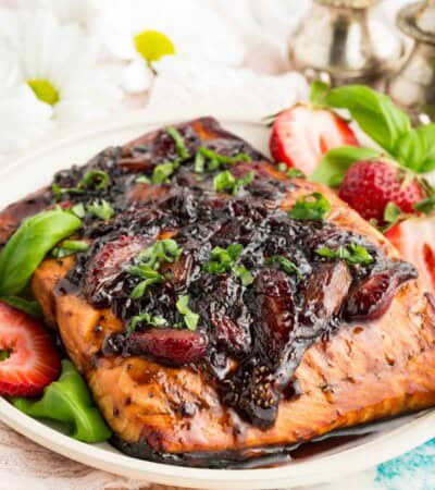 Balsamic strawberry glaze drip down a flaky piece of salmon.