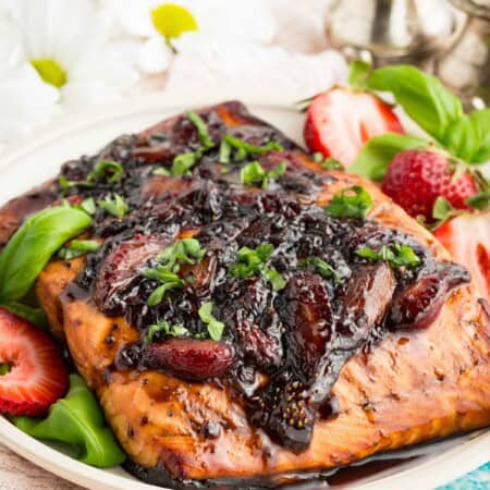 Balsamic strawberry glaze drip down a flaky piece of salmon.