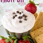 A small dish of creamy yogurt dip surrounded by berries and graham crackers with text overlay that says "Strawberry Fruit Dip".