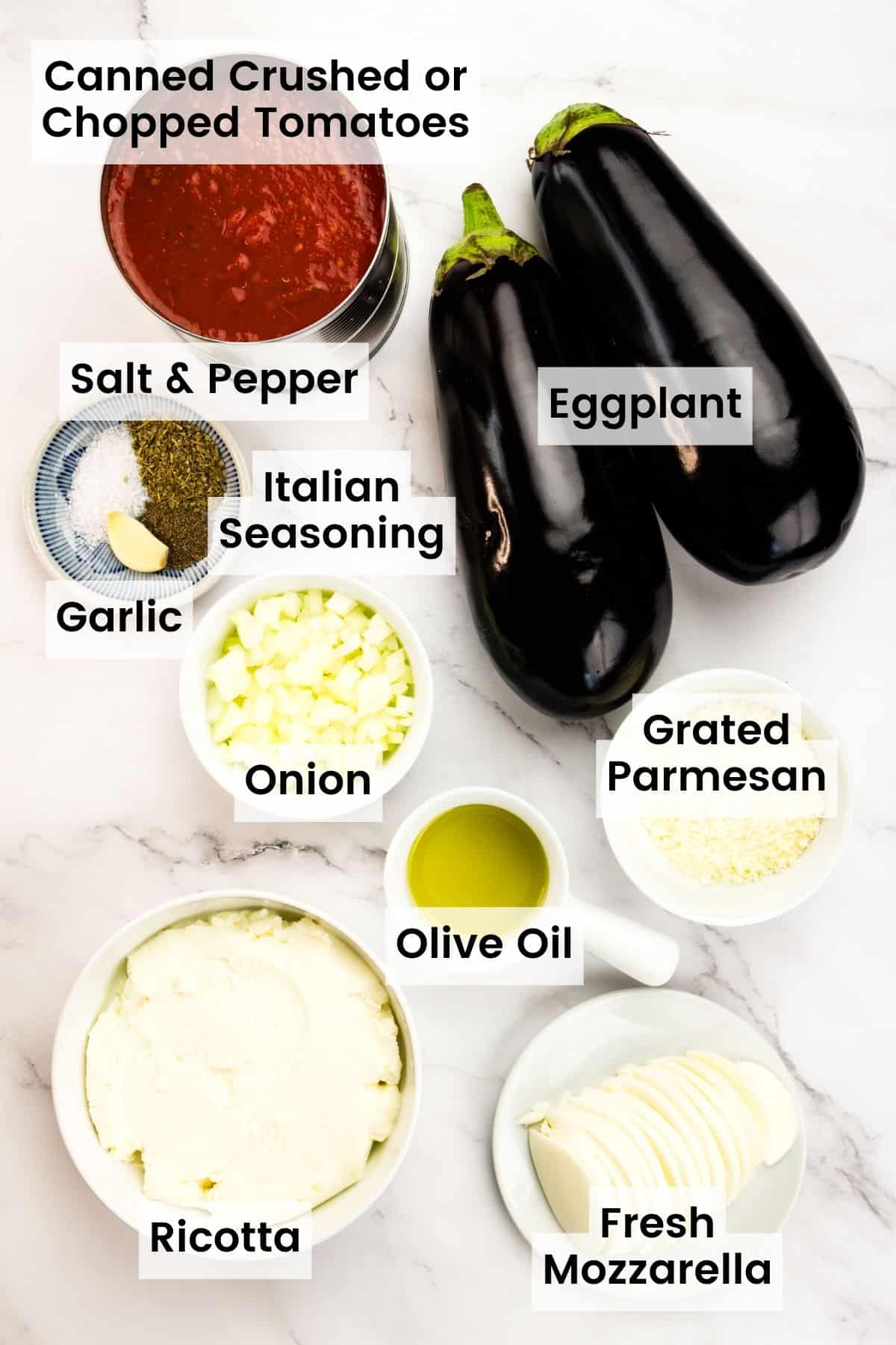 The ingredients for stuffed eggplant parmesan are shown labelled: eggplant, salt and pepper, canned tomatoes, Italian seasoning, parmesan, mozzarella, olive oil, onion, garlic, ricotta.