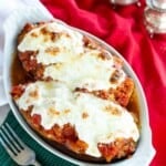 Stuffed eggplant parmesan topped with melted cheese in a serving dish.