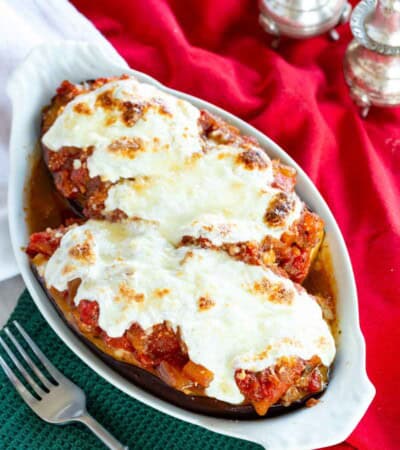 Stuffed eggplant parmesan topped with melted cheese in a serving dish.