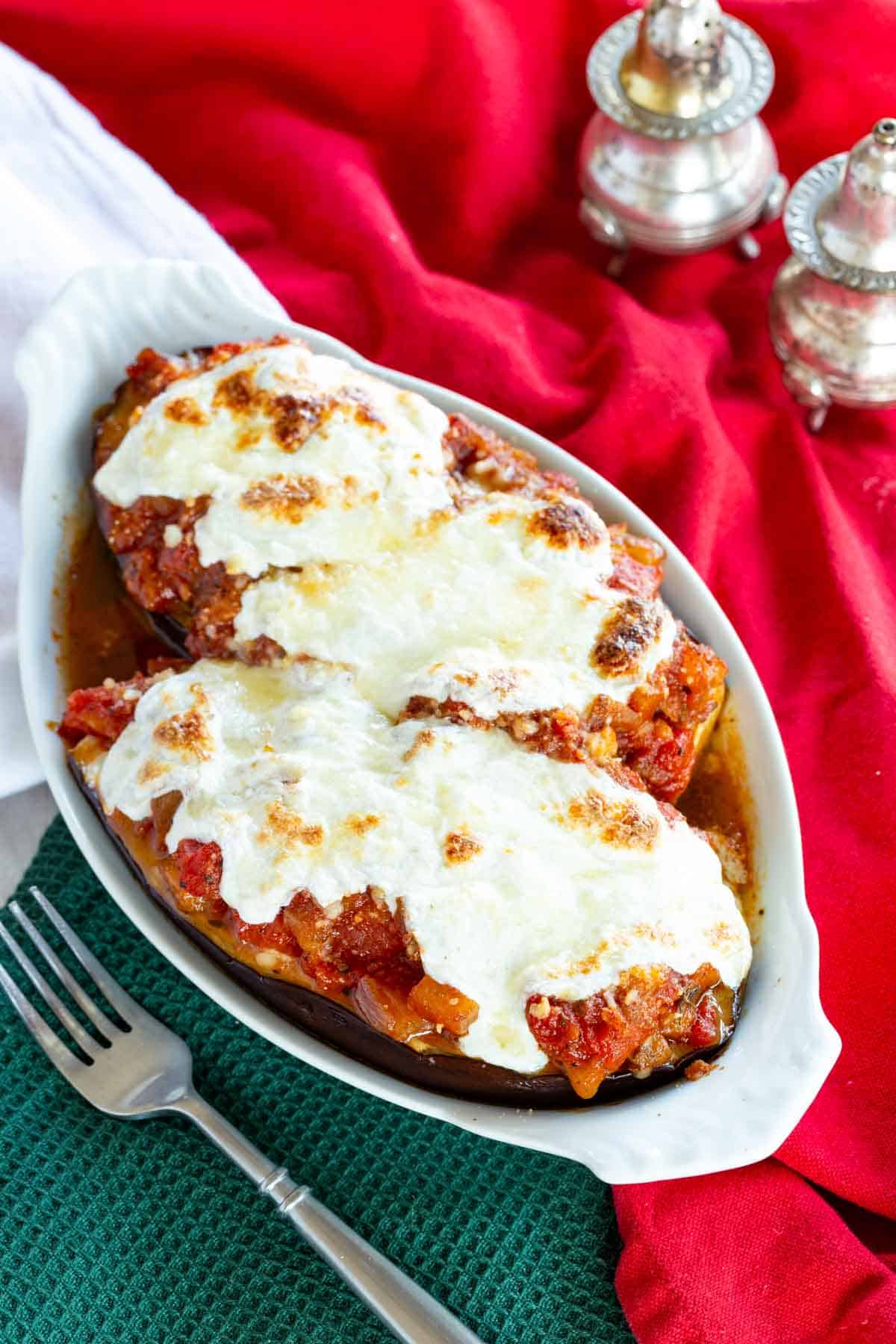 Stuffed eggplant parmesan topped with melted cheese in a serving dish.