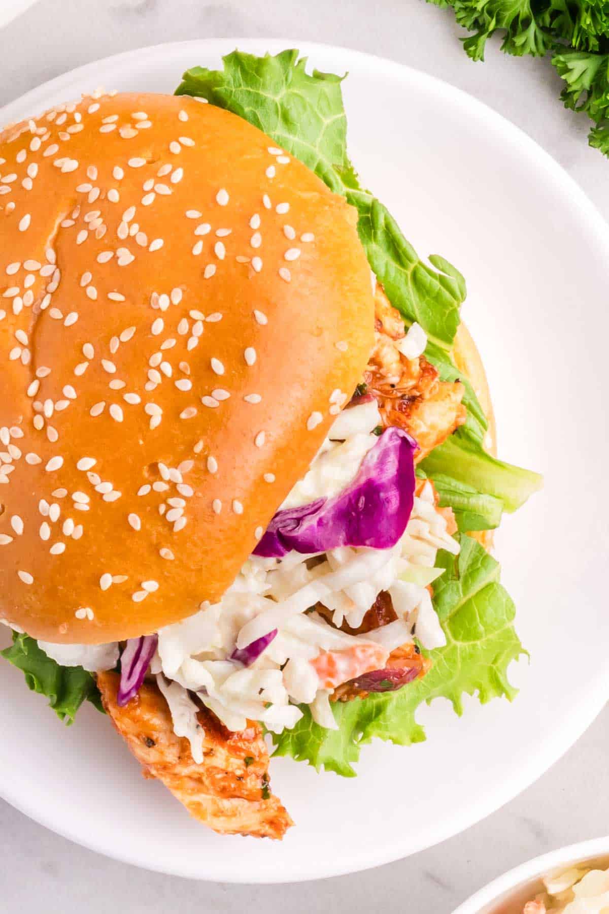 A sesame seed-flecked bun is used to serve a bbq chicken sandwich.