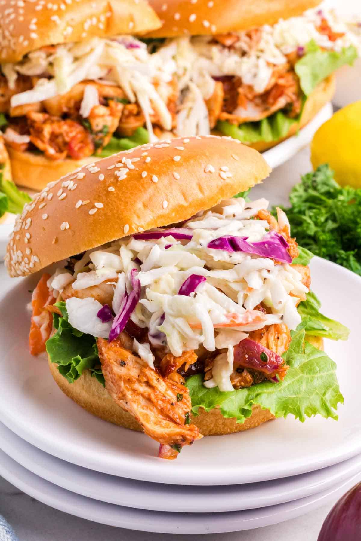 The filling of a bbq chicken sandwich can be seen including chicken and coleslaw.