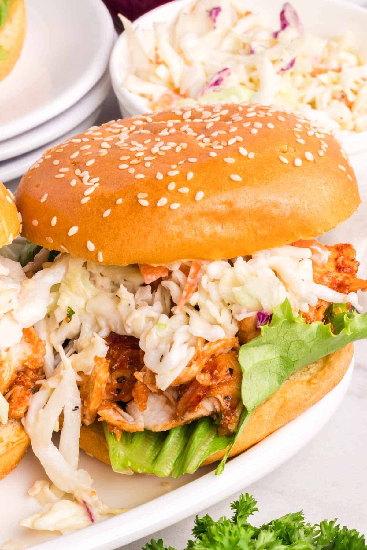 Chicken, lettuce, and coleslaw make up a bbq chicken sandwich.