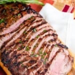 A sliced grilled flank steak on a cutting board with text overlay that says "Balsamic Marinated Flank Steak".