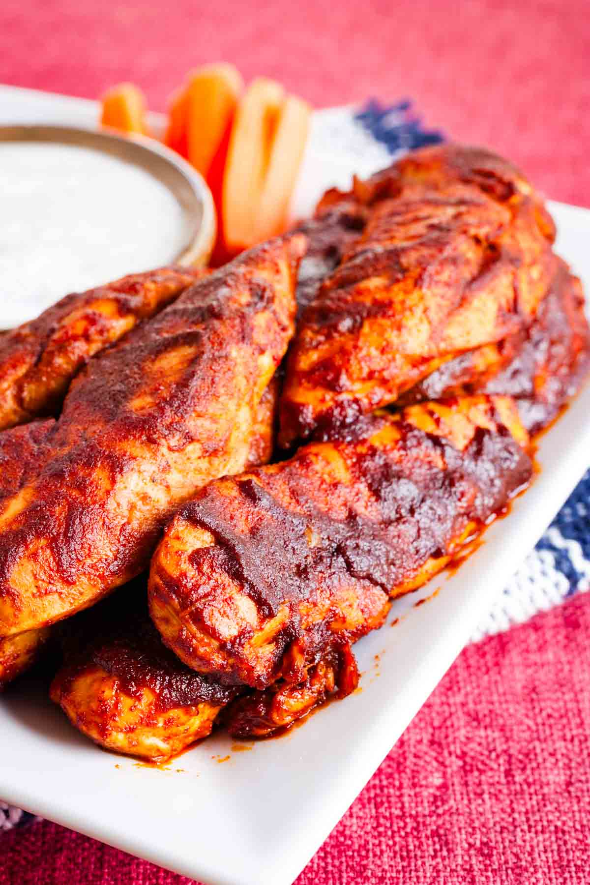 Caramelized and seasoned buffalo chicken tenders are served on a white plate.