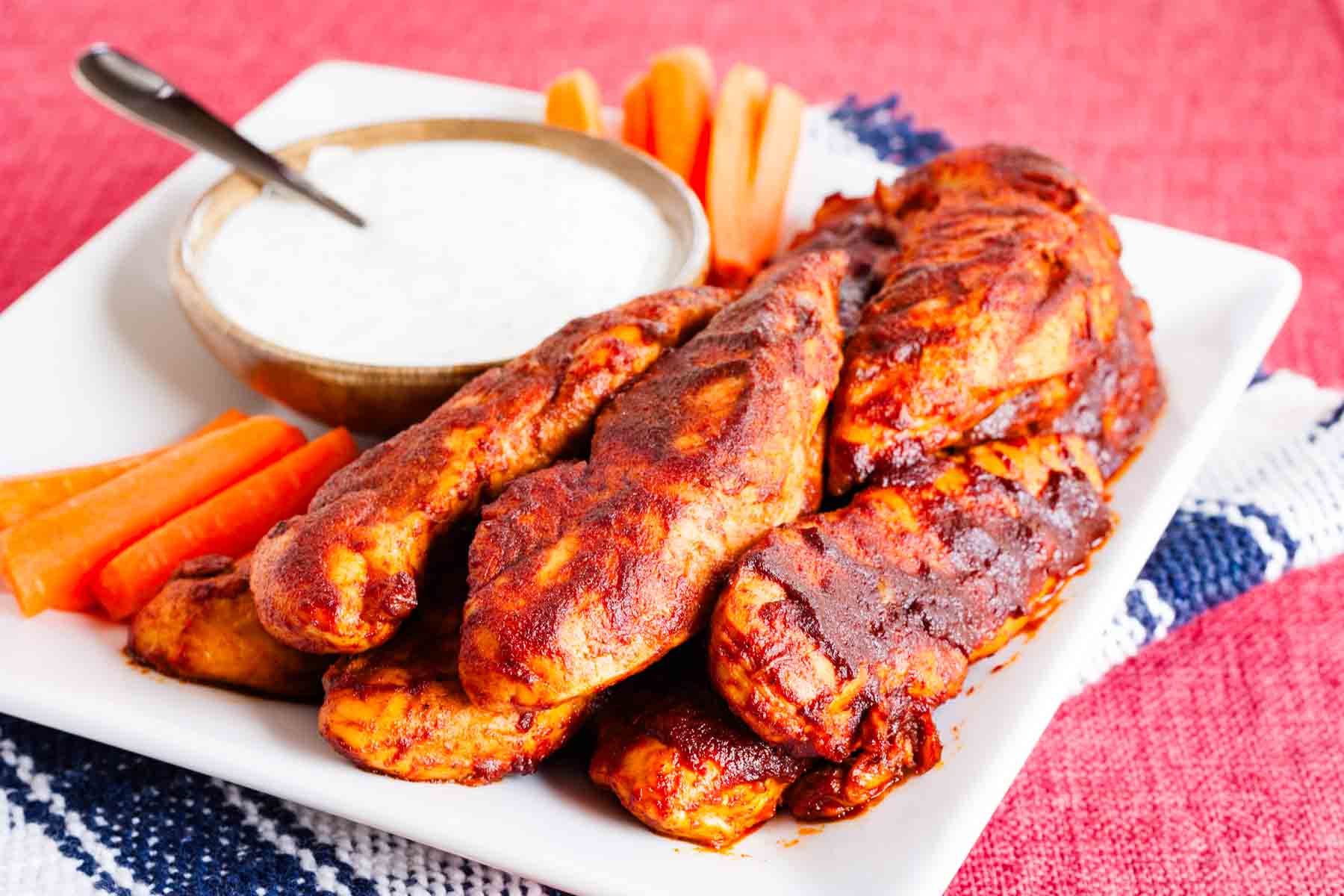 Dipping sauce is served on a serving plate with buffalo chicken tenders.