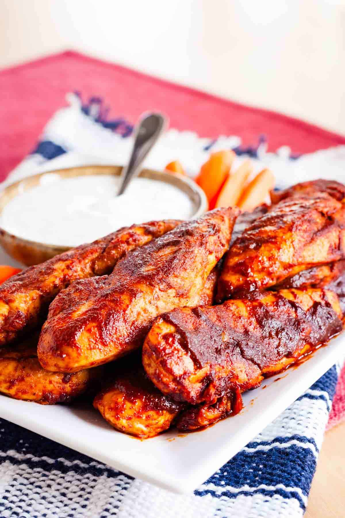 Buffalo chicken tenders are served with a bowl of dipping sauce.