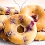 A gluten free blueberry donut is turned on its side in front of more donuts.