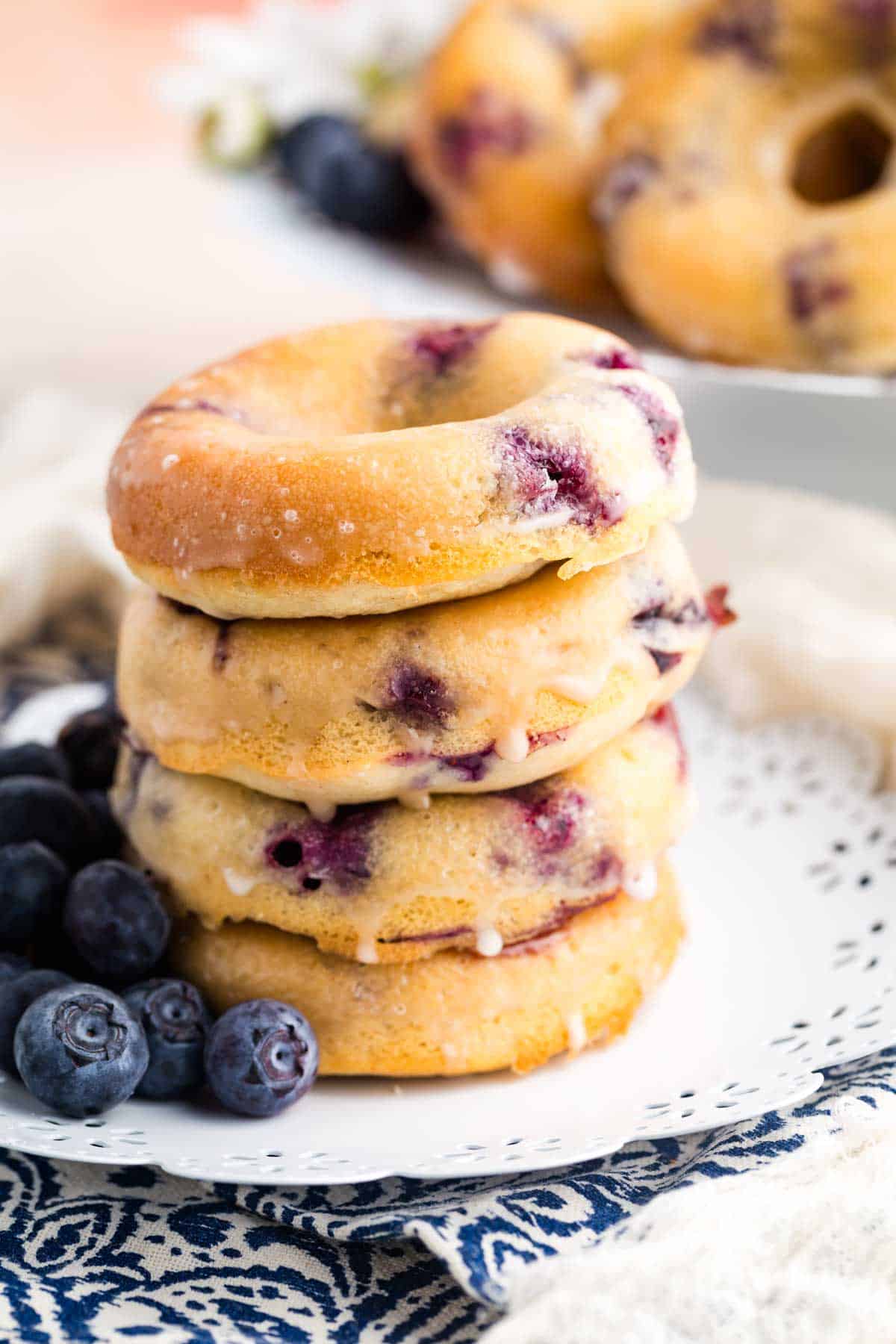 A stack of gluten free blueberry donuts with more blueberries.