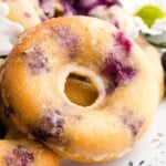 A closeup of a baked donut with glaze with text overlay that says "Gluten Free Blueberry Donuts".