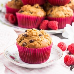 A gluten free raspberry muffins with mini chocolate chips in a pink wrapper on a small plate.