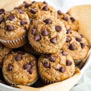 Chocolate chip zucchini muffins with chocolate chips piled in a bowl.