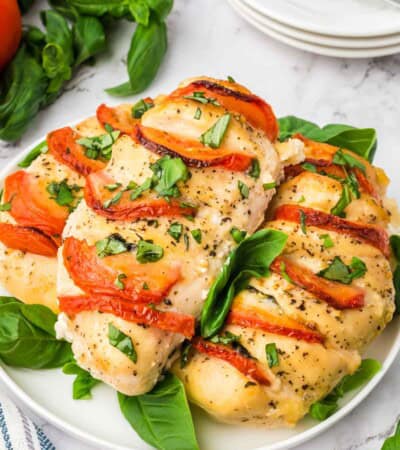 Three stuffed caprese chicken breasts on a white plate.
