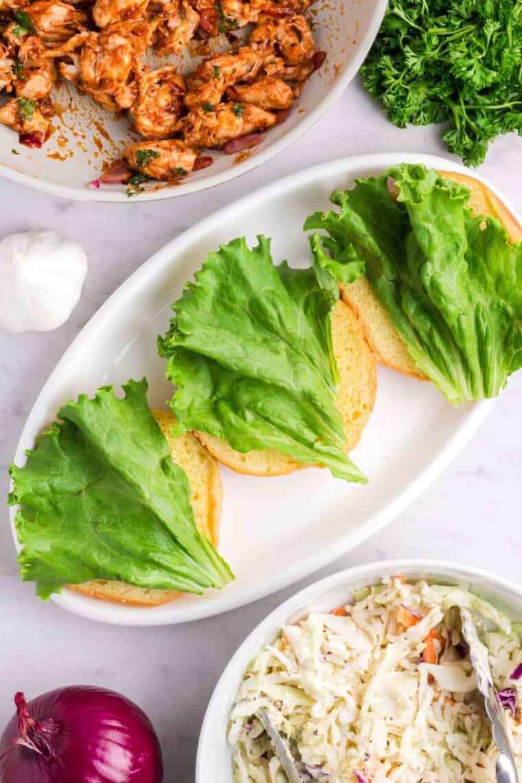 Pieces of lettuce are placed on the bottom halves of the buns.