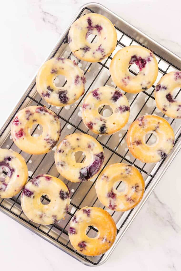 One dozen gluten free blueberry donuts cool on a wire rack.