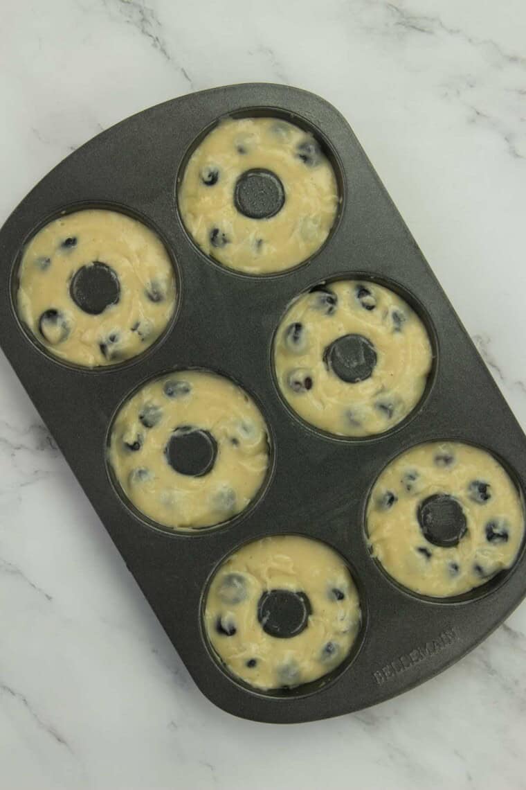 Gluten free blueberry donut batter is added to a baking pan.