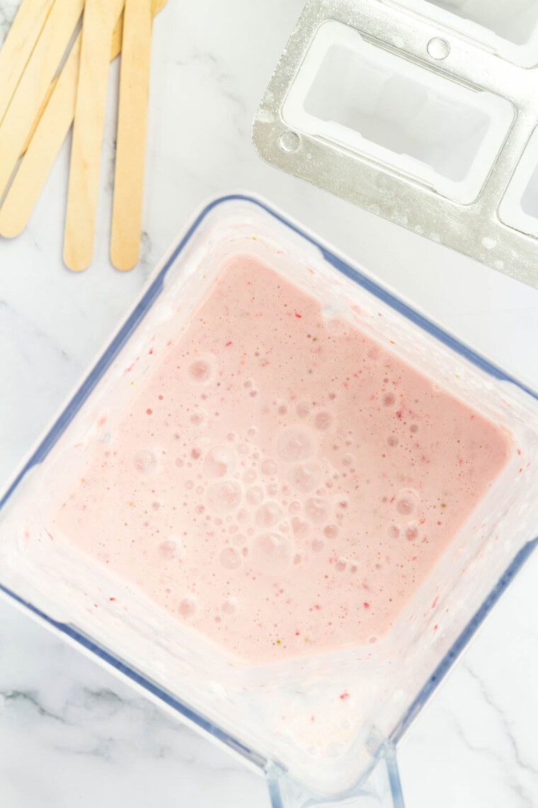 The pink popsicle mixture in a blender.