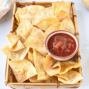 A tray of air fryer tortilla chips with a bowl of tomato salsa.