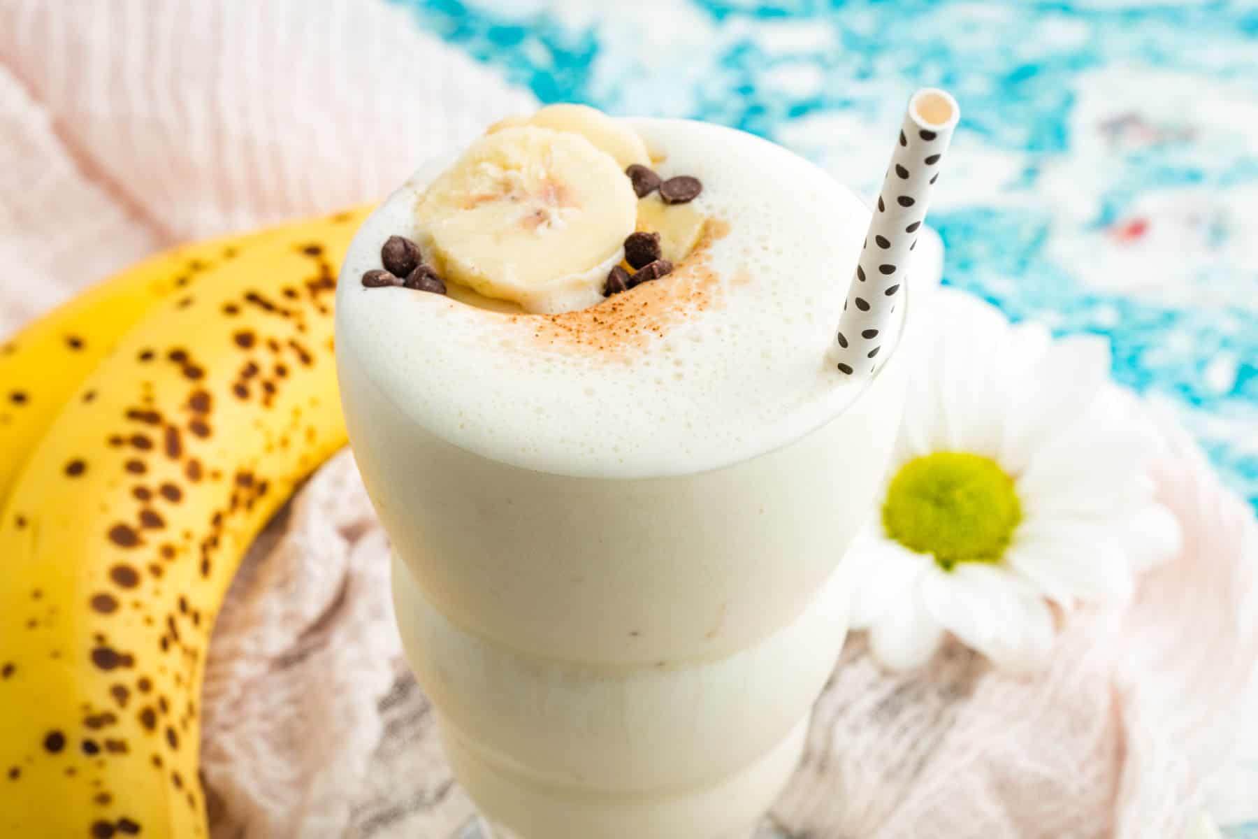 A banana is seen alongside a glass of banana smoothie.