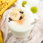 A banana is seen alongside a glass of banana smoothie.