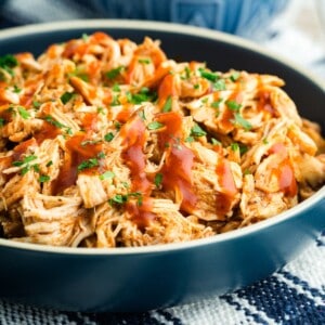 A bowl of shredded BBQ chicken drizzled with barbecue sauce.