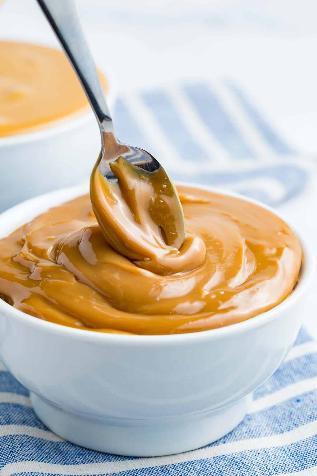 A spoon dips into a bowl of dulce de leche.