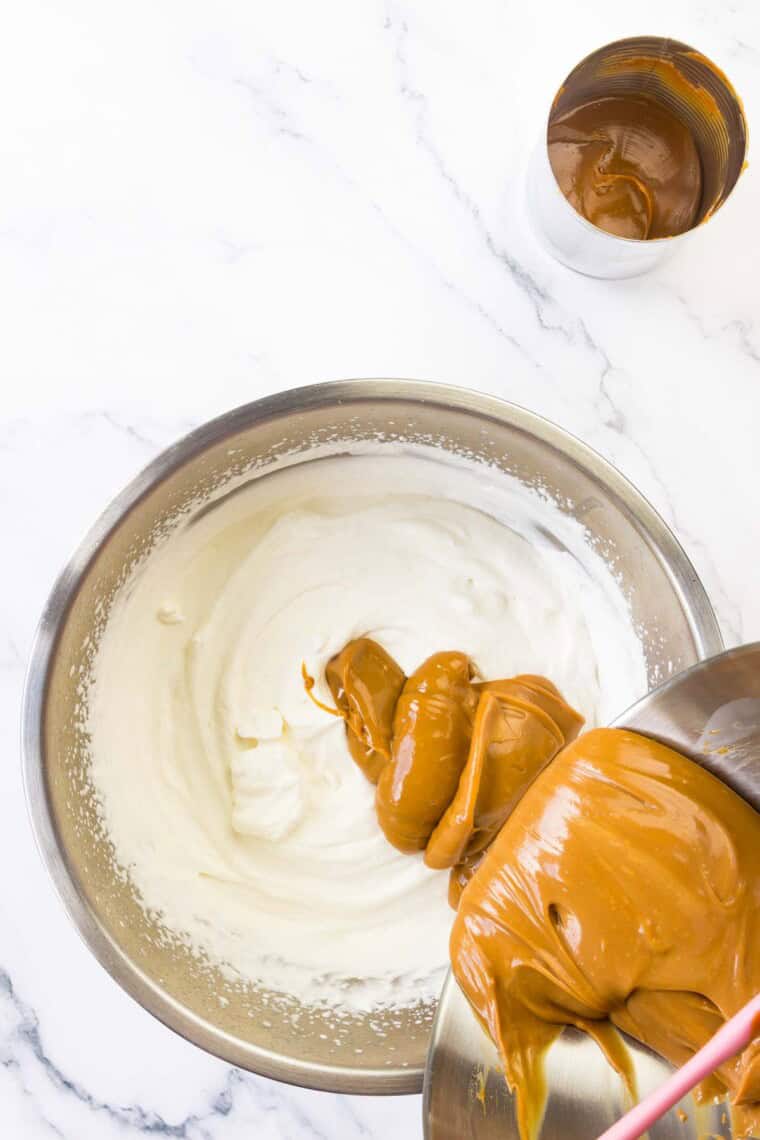 A can of dulce de leche is poured into the whipped cream mixture.