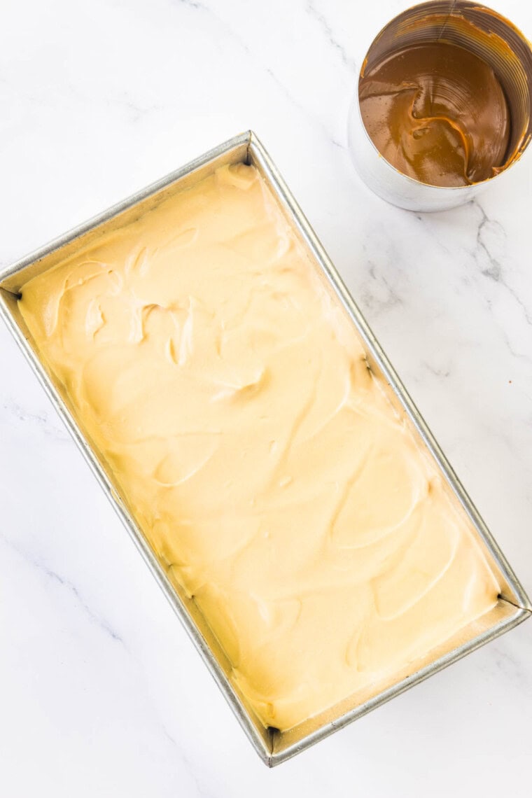The base for dulce de leche ice cream in a loaf pan with a can of dulce de leche next to it.