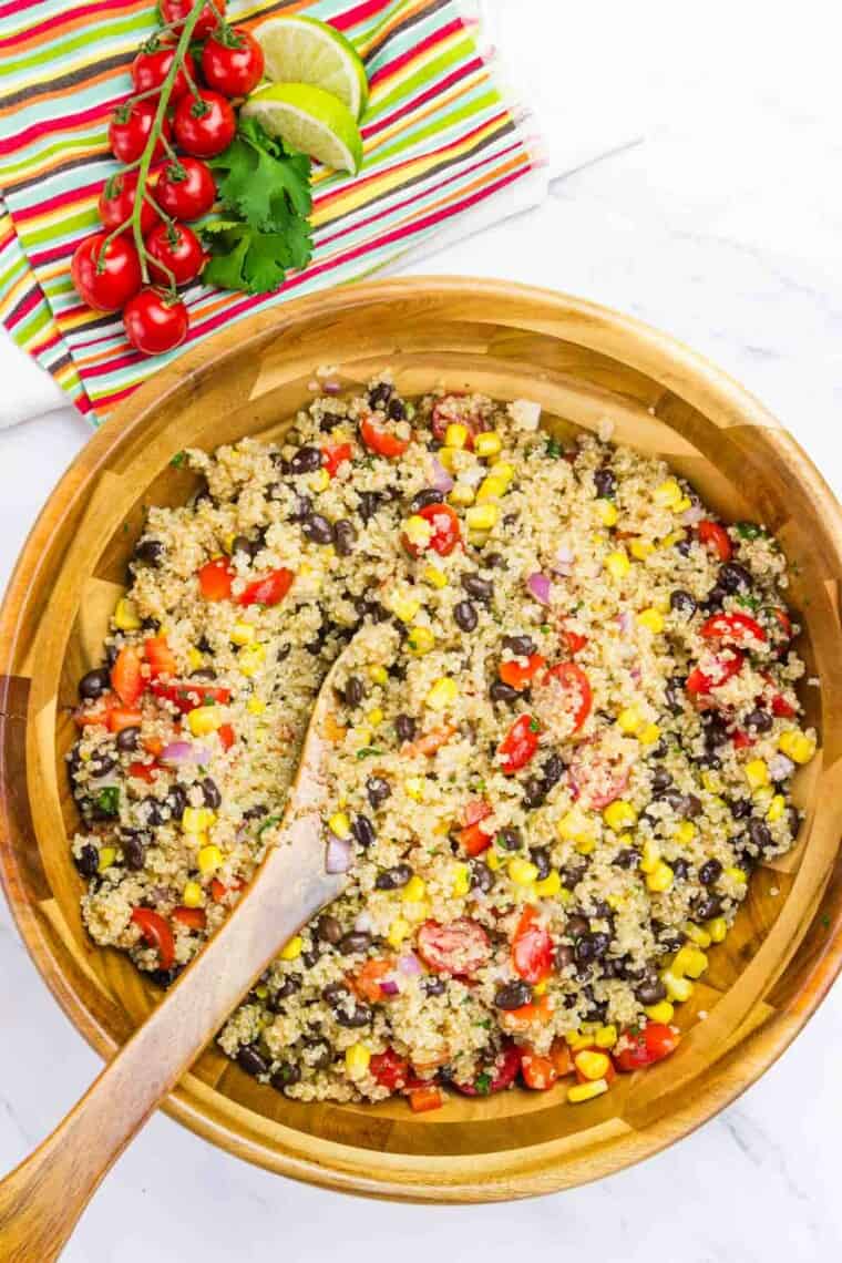 A spoon stirs a bowl of Mexican quinoa salad.