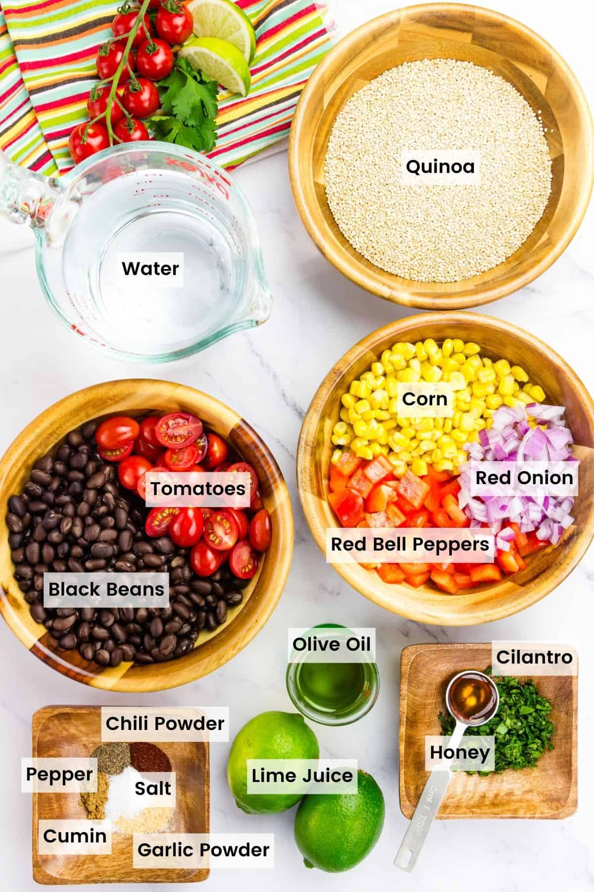 Ingredients for Mexican quinoa salad are portioned and labeled: quinoa, water, tomatoes, black beans, corn, red onion, bell peppers, cilantro, lime juice, spices, olive oil, salt and pepper.