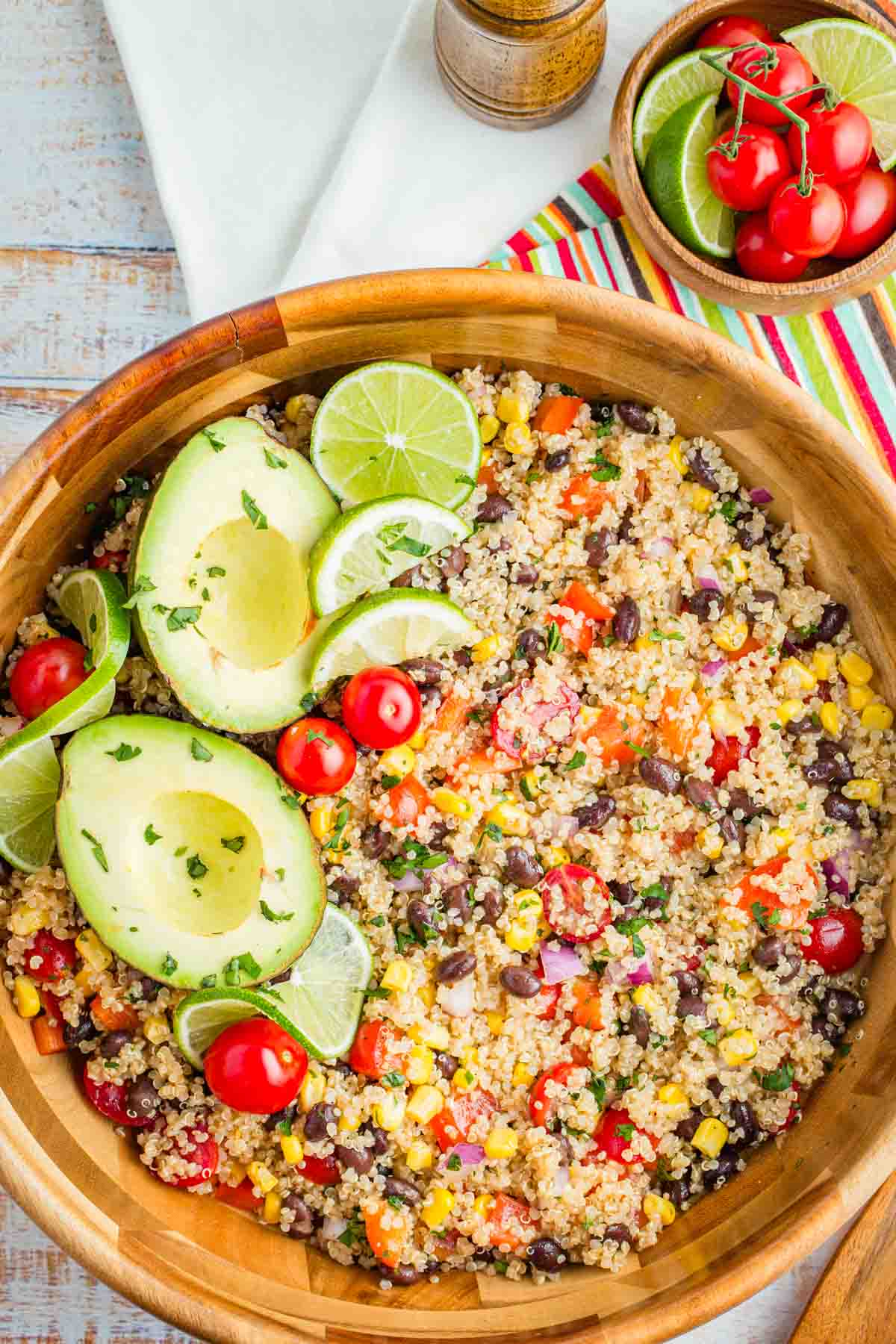 A bowl of Mexican quinoa salad in a serving bowl topped with lime and avocado.