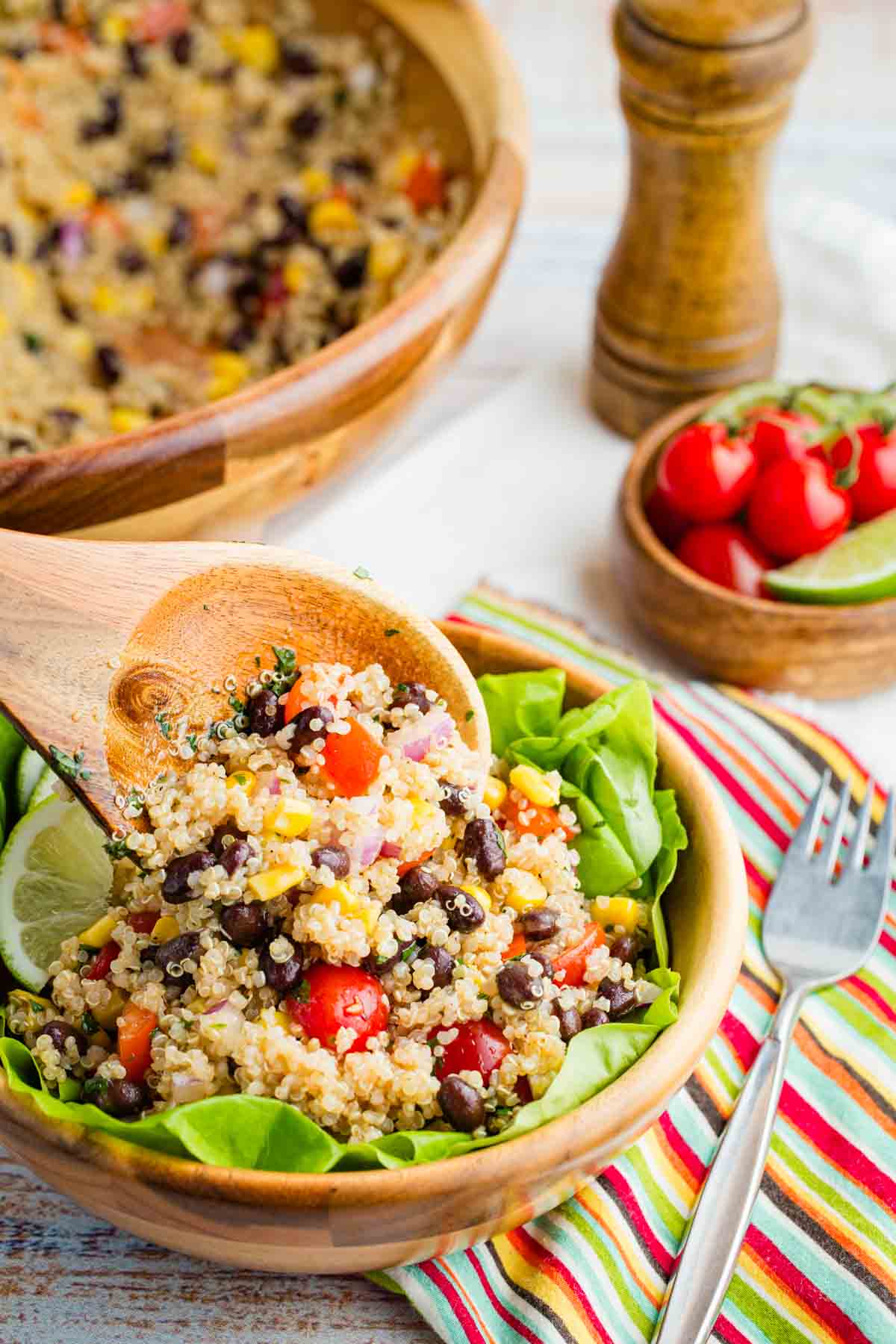 Mexican quinoa salad is seen on a serving spoon above a bowl of salad.