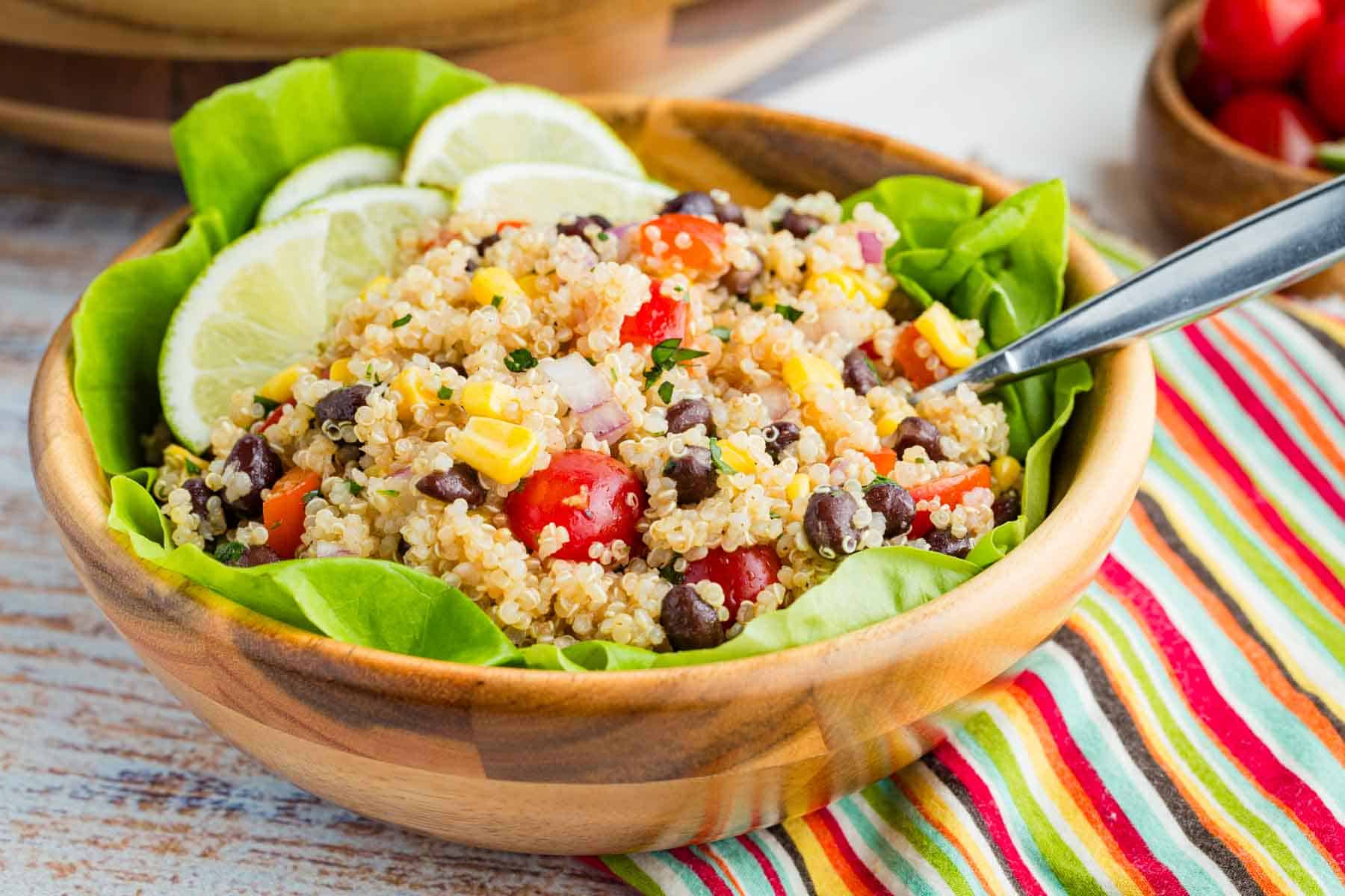 A portion of quinoa salad is served in a bowl with the bigger bowl of salad behind it.