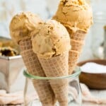 A glass container holds three cones of dulce de leche ice cream.