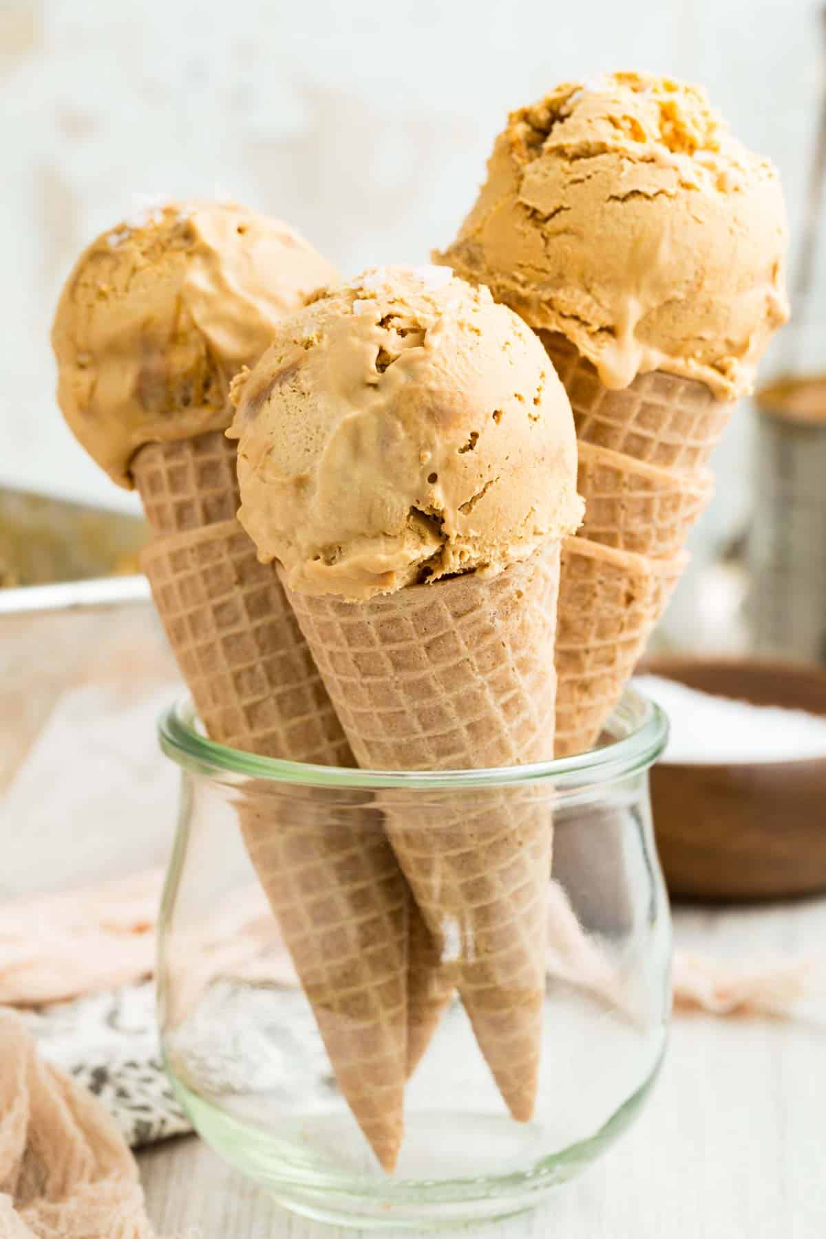 Three cones of dulce de leche ice cream in a glass container.