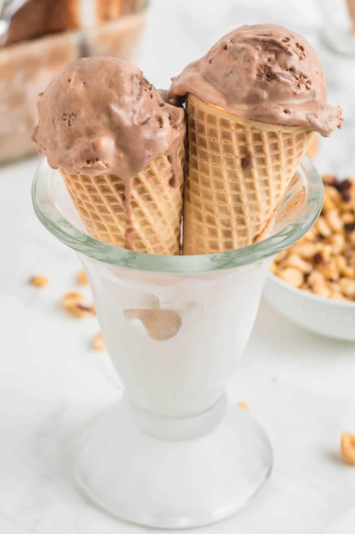 A glass serving container holds two cones of nutella ice cream.