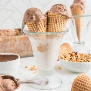 A glass serving container holds two cones of nutella ice cream.