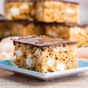 A peanut butter rice krispie treat on a small square plate.