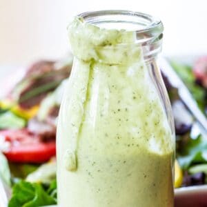 Avocado ranch dressing drips down the side of a bottle of dressing.