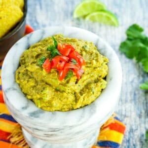 A bowl of easy guacamole is topped with chopped tomatoes.