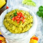 A marble bowl holds creamy easy guacamole and tomatoes.