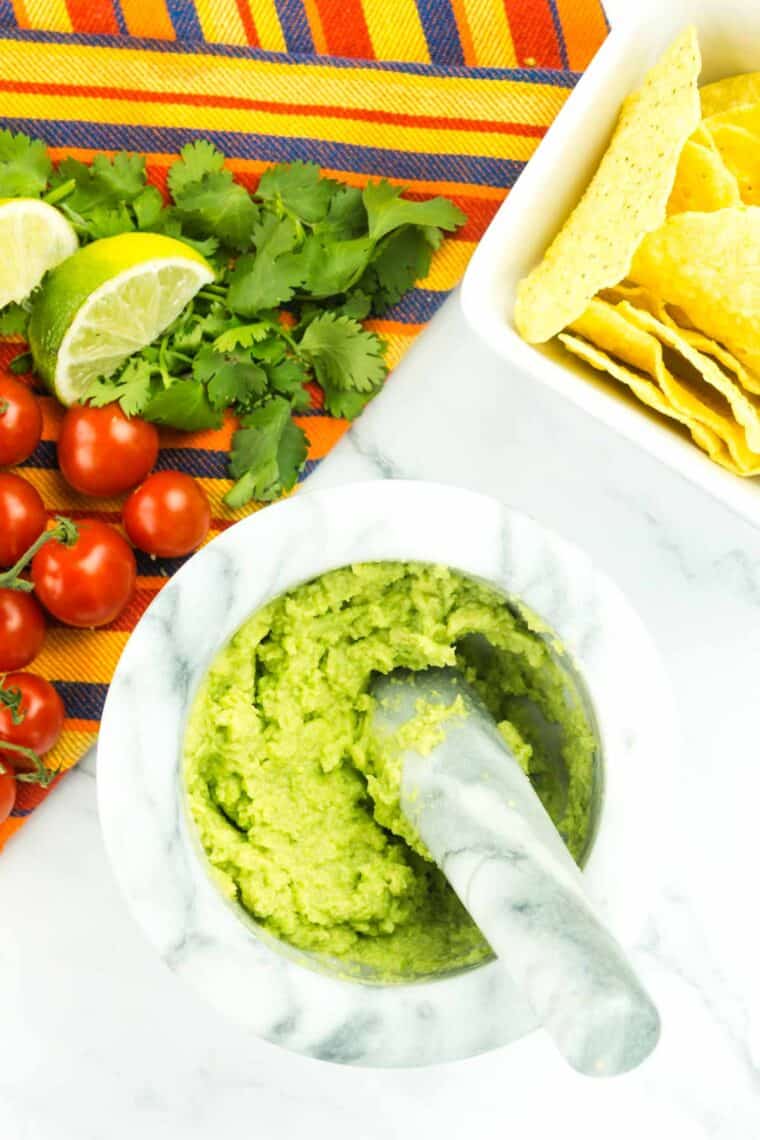 A pestle is used to mash up avocado.