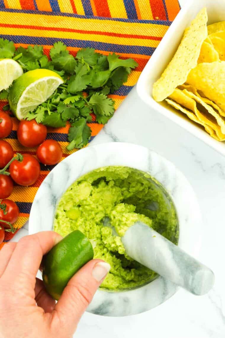 Lime juice is squeezed over the mashed avocado.