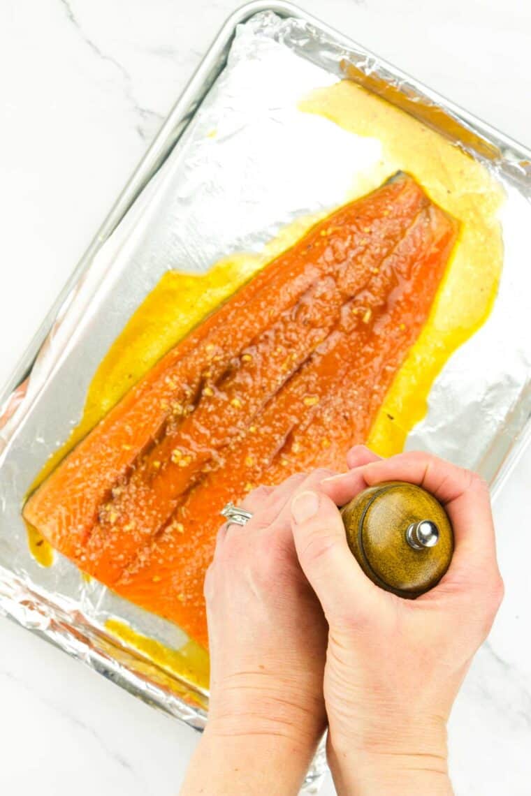 Using a pepper mill to season salmon.