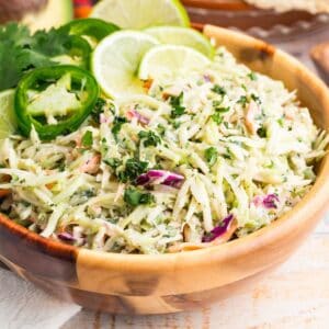 Thinly sliced limes top a bowl of colorful taco slaw.