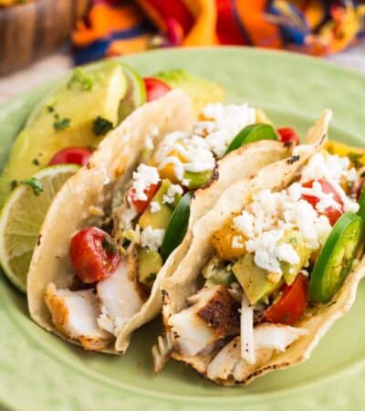 Tilapia fish tacos on a plate with toppings.