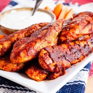 Glazed Buffalo chicken tenders on a white plate.